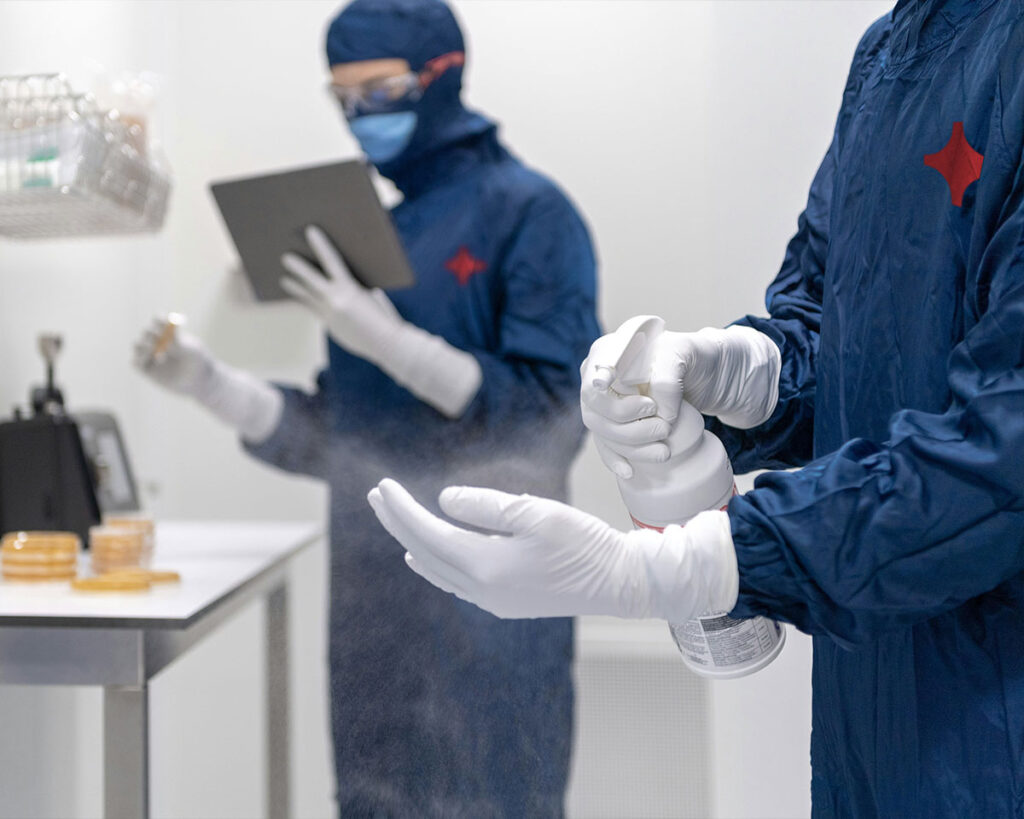 Person with PPE spraying a cleaning liquid on their hand